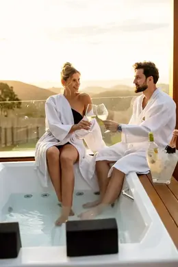 Casal brindando na banheira com vista para a serra