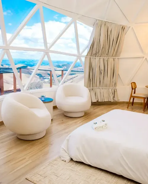 Cama de casal dentro do domo, com janelas triangulares para a serra